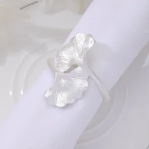 Matte silver ginkgo leaf napkin ring with detailed texture on a white cloth