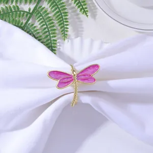 Detailed close-up of a pink dragonfly napkin ring with a gold alloy finish on white linen