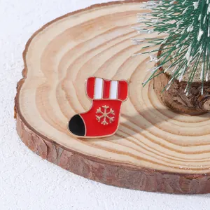Spilla smaltata a forma di calza di Natale con fiocco di neve dorato su legno