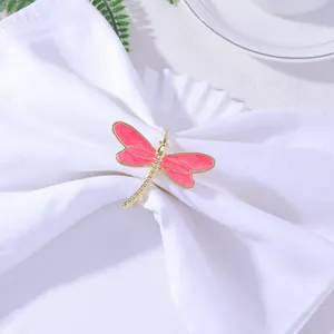 Macro detail of a golden dragonfly napkin ring with pink enamel on a white linen napkin