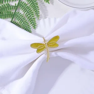 Detailed close-up of a golden dragonfly napkin ring with yellow enamel wings on white cloth