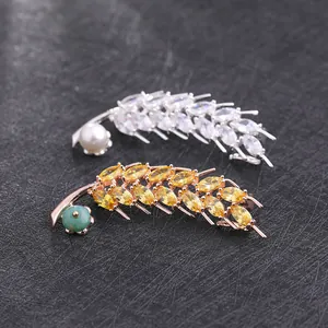 Vue macro détaillée de broches plumes en argent et or rose avec zircon et perles