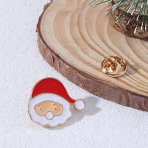 Dettaglio della spilla Babbo Natale in smalto con chiusura a farfalla dorata su sfondo