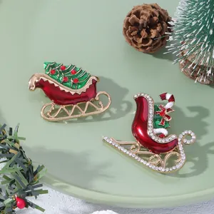 Exquisite Christmas sled brooches with rhinestones and enamel on a festive green display