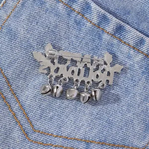 Silver Hellstar brooch with five small bells on a blue denim background close-up