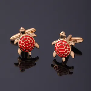 Macro shot of gold turtle cufflinks with red enamel pattern on a reflective black base
