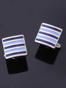 Macro shot of square silver cufflinks with blue striped enamel on a black reflective surface