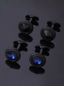 Détail de boutons de manchette ronds en métal noir avec cristaux bleus et noirs sur miroir