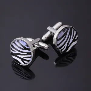 Polished silver cufflinks with black and white zebra pattern on black reflective background