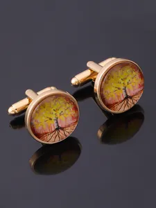 Close-up of golden Tree of Life cufflinks with autumn colors on a black mirror surface