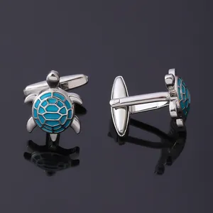Detailed view of silver sea turtle cufflinks with teal enamel shell on dark reflective surface