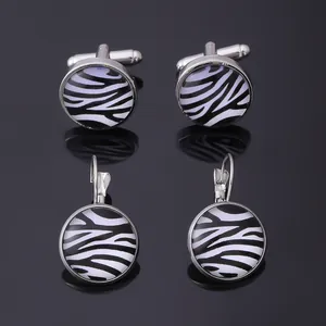Close-up of zebra pattern cufflinks and earrings set with polished silver metal finish