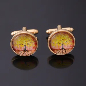 Close-up of golden Tree of Life cufflinks with colorful enamel on a black reflective surface