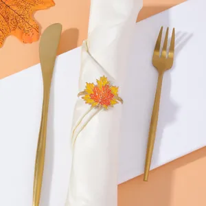 Detailed close-up of a maple leaf napkin ring with orange gradient finish on a white napkin