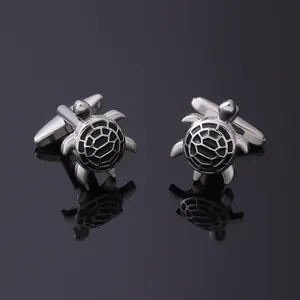 Silver turtle cufflinks with black enamel shell details on a reflective background