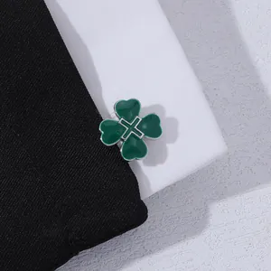 Detailed macro view of a green heart-shaped clover cufflink on black textured fabric