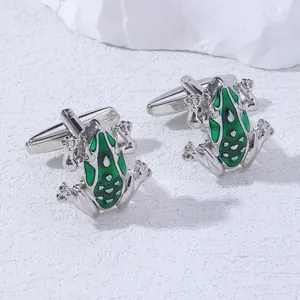 Macro shot of silver frog cufflinks featuring green enamel and detailed skin patterns