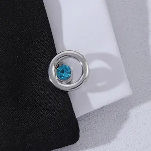 Detailed close-up of a silver round cufflink with a sky blue crystal on dark fabric