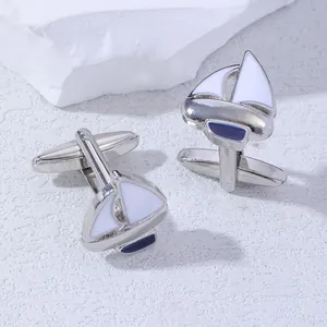 Detail of silver sailboat cufflinks with white and blue enamel on a textured base