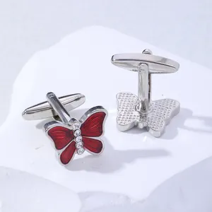 Macro detail of red enamel butterfly cufflinks with crystal rhinestones on stone background