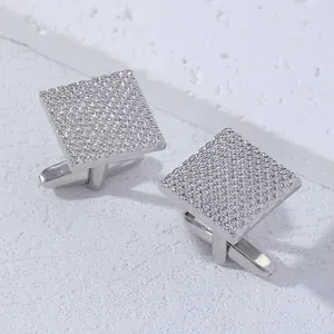 Detailed close-up of square silver cufflinks with textured woven pattern on stone surface