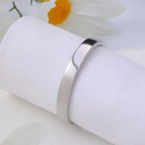 Close-up of polished silver metal napkin ring on white fabric with floral accents