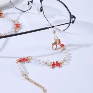 Detail view of pearl eyewear chain with red butterfly charms and non-slip loops