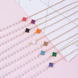 Colorful four-leaf clover eyeglass chains with pearls on a pink decorative background