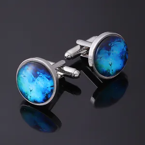 Macro shot of silver cufflinks with blue nebula glass dome on reflective black surface