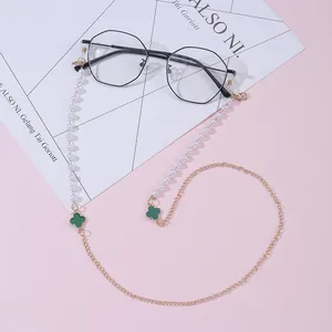 Detail of eyewear chain with green clover charms, white pearls and gold metal links