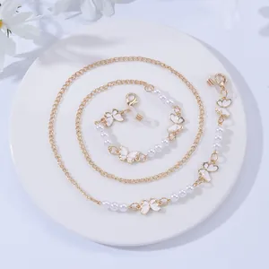 Detail view of gold glasses chain with white enamel butterfly pendants and pearls