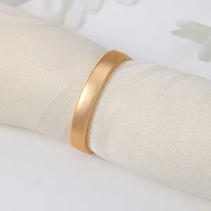 Servilletero dorado mate en forma de D sobre tela blanca para decoración de mesa