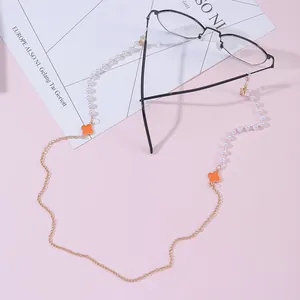 Detail of beaded glasses chain with orange clover charms and golden lobster clasps