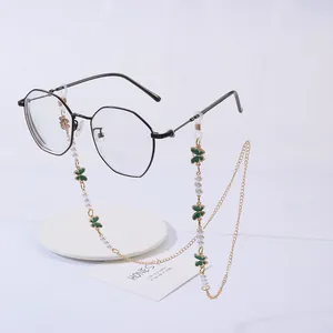 Detail of beaded glasses chain with gold links, white pearls and green enamel butterfly