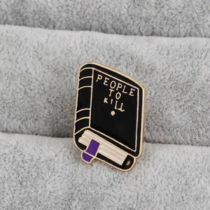 Macro de broche de libro en esmalte negro People To Kill con borde dorado en terciopelo
