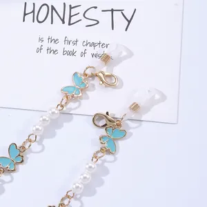 Detail of gold metal chain with blue enamel butterflies and white imitation pearls
