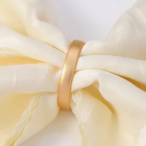Primer plano de un servilletero dorado mate con elegante detalle de tela crema