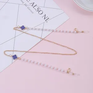 Detail of clover eyewear chain with purple charms and white pearls on pink background