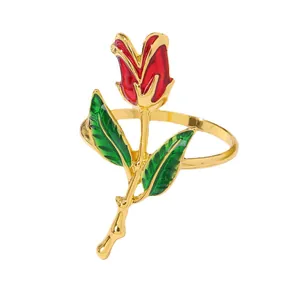 Elegante servilletero de rosa roja con acabado dorado y hoja esmaltada verde sobre blanco