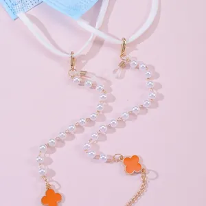 Four-leaf clover glasses chain and mask holder with pearls on soft pink background