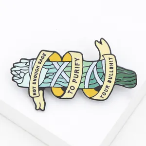 Detail van emaille pin met saliebundelontwerp en humoristische tekst op wit
