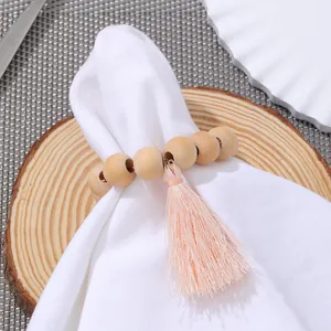Serviettenring aus Holzperlen mit rosa Quaste auf weißer Serviette für Tischdeko