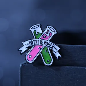Macro shot of chemistry test tube enamel pins with pink and green liquid and text banner