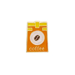 Detailed view of an orange enamel coffee bag pin with bean icon and coffee text