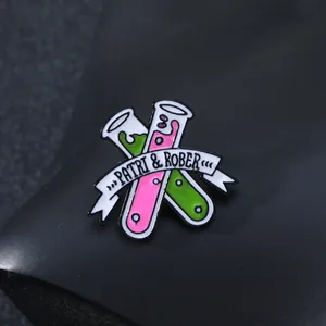 Science lab enamel pin with crossed test tubes and ribbon detail on a dark background