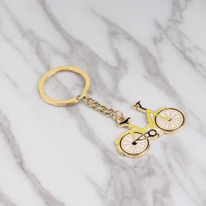 Dettaglio portachiavi a forma di bicicletta gialla smaltata con finitura dorata su marmo