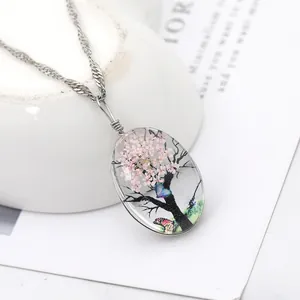 Détail du pendentif ovale en verre avec fleurs séchées roses et chaîne torsadée argentée