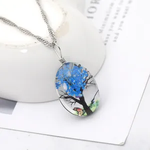 Gros plan d'un pendentif ovale en résine avec fleurs séchées bleues et chaîne