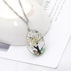 Pendentif vintage en verre avec fleurs séchées blanches et papillon sur chaîne argent