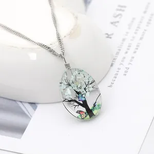 Vue macro d'un pendentif ovale en résine avec des fleurs séchées et un motif de papillon